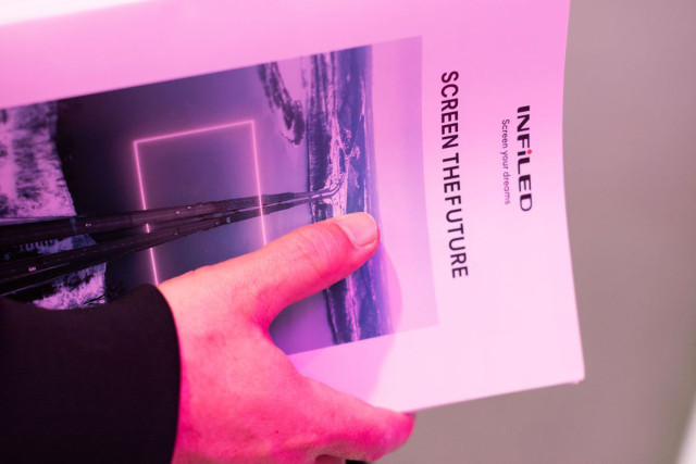 Hand holding a dossier of papers on which we can read 'Infiled, screen the future'