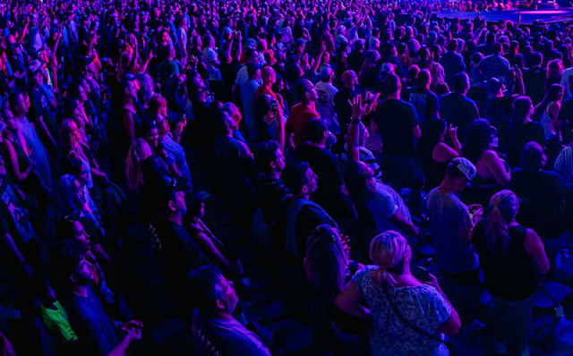 Crowd of people at an event illuminated by purple and blue lights