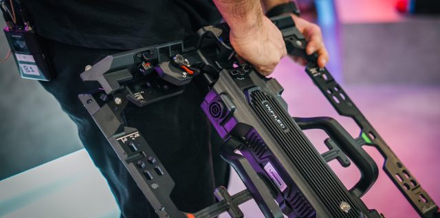 A technician carrying an INFiLED rental LED cabinet with one hand.